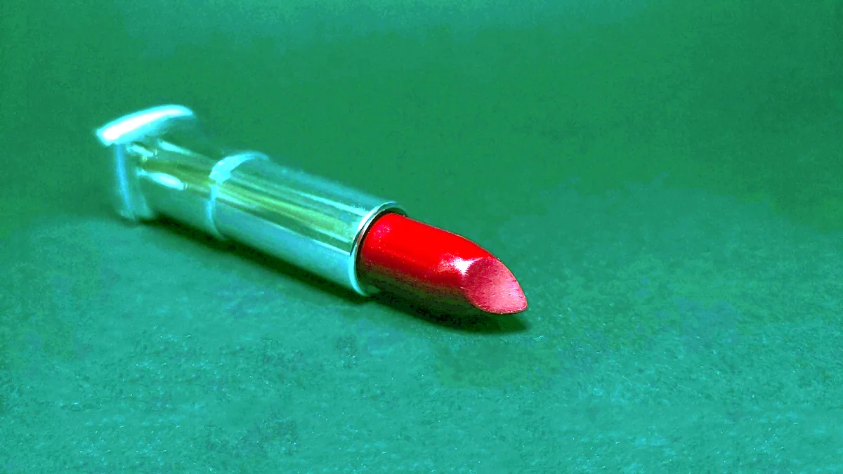 Eine geöffnete rote Lippenstift auf dunklem Grund, das Gold der Fassung glänzt.